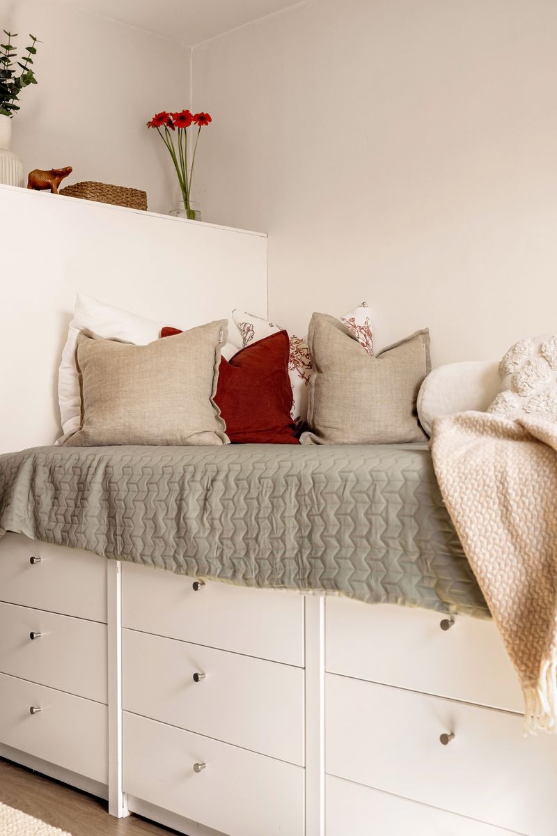 Cozy minimalist bedroom with layered pillows and warm ambient lighting