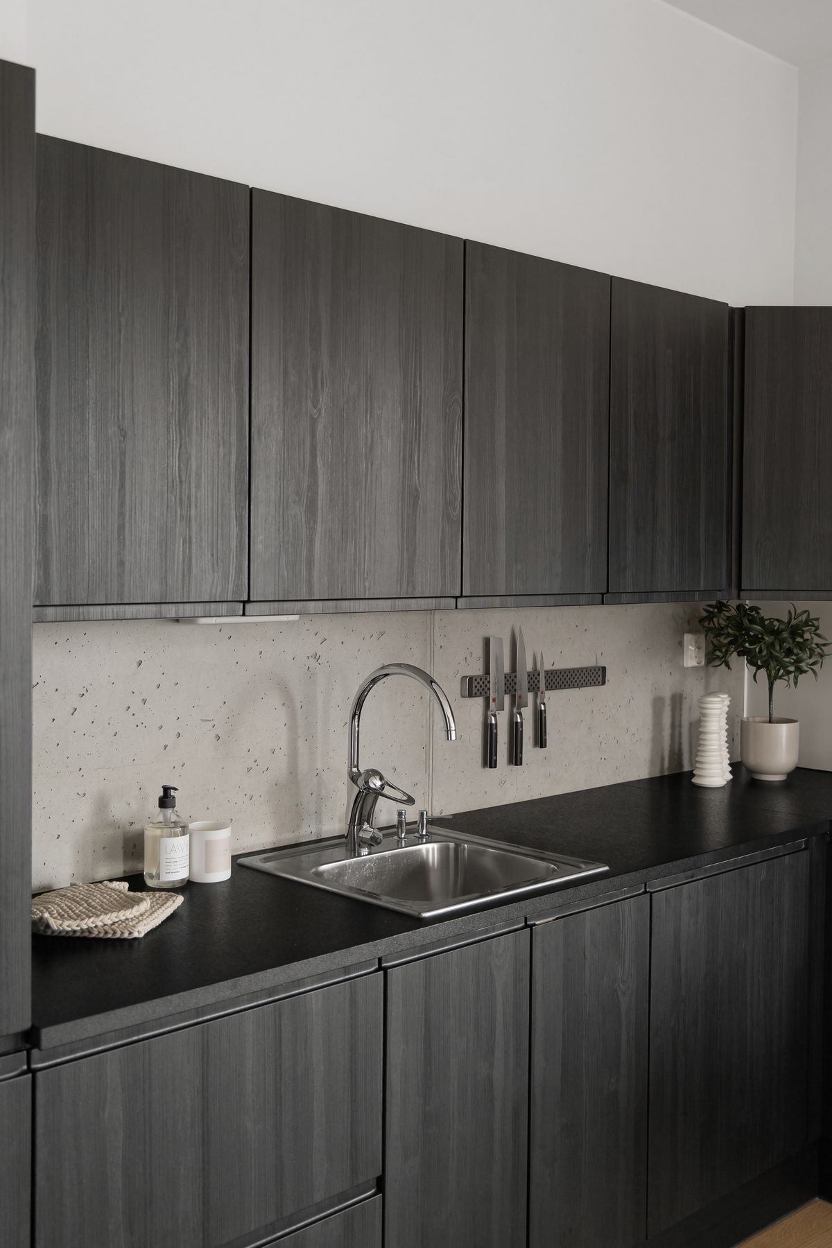 Sleek kitchen sink and faucet installed against dark wooden cabinets