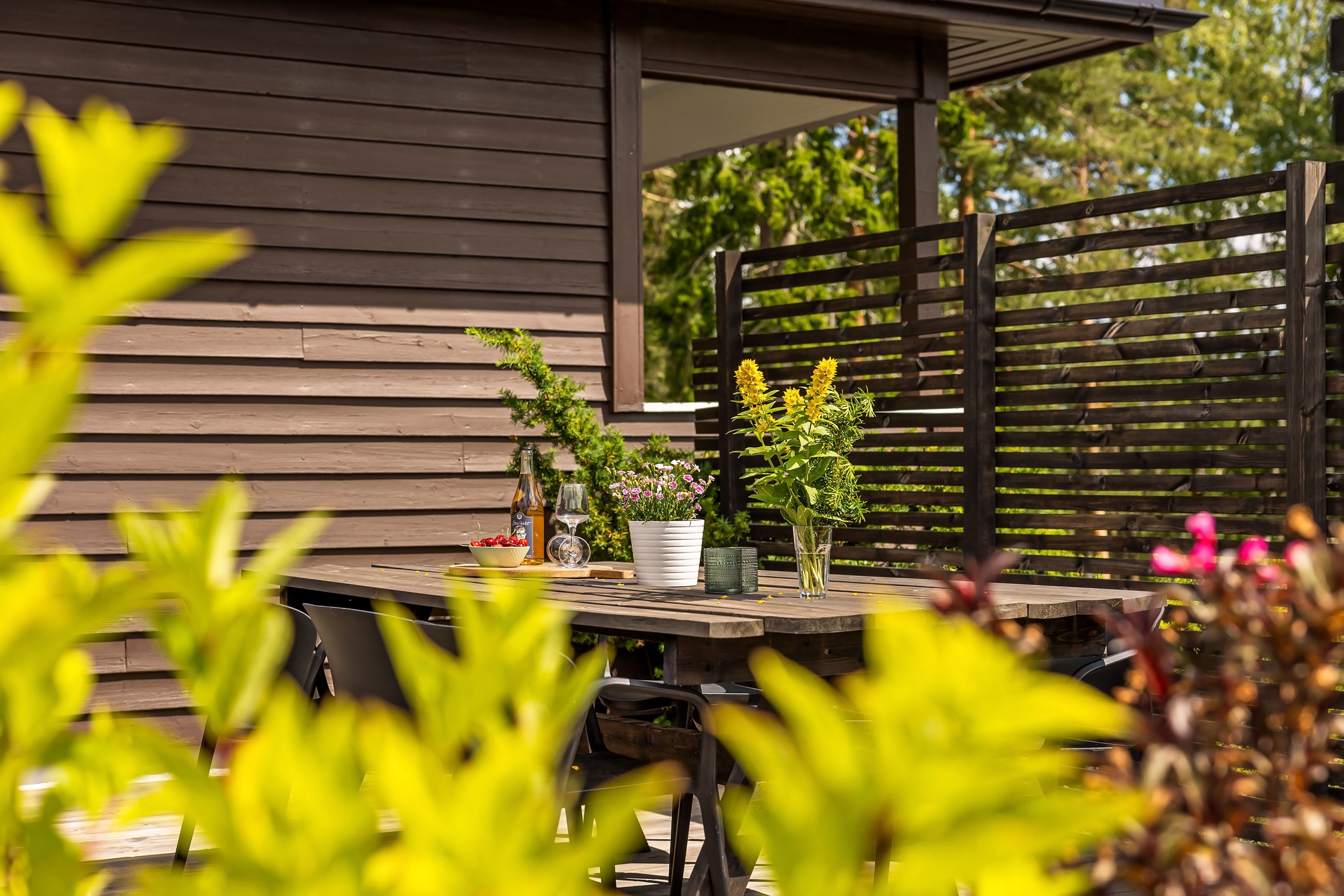 Cozy outdoor patio with wooden table, chairs, and fresh flowers in sunlight