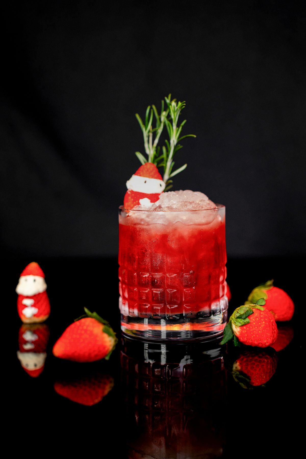 Strawberry cocktail with rosemary and ice on a dark background
