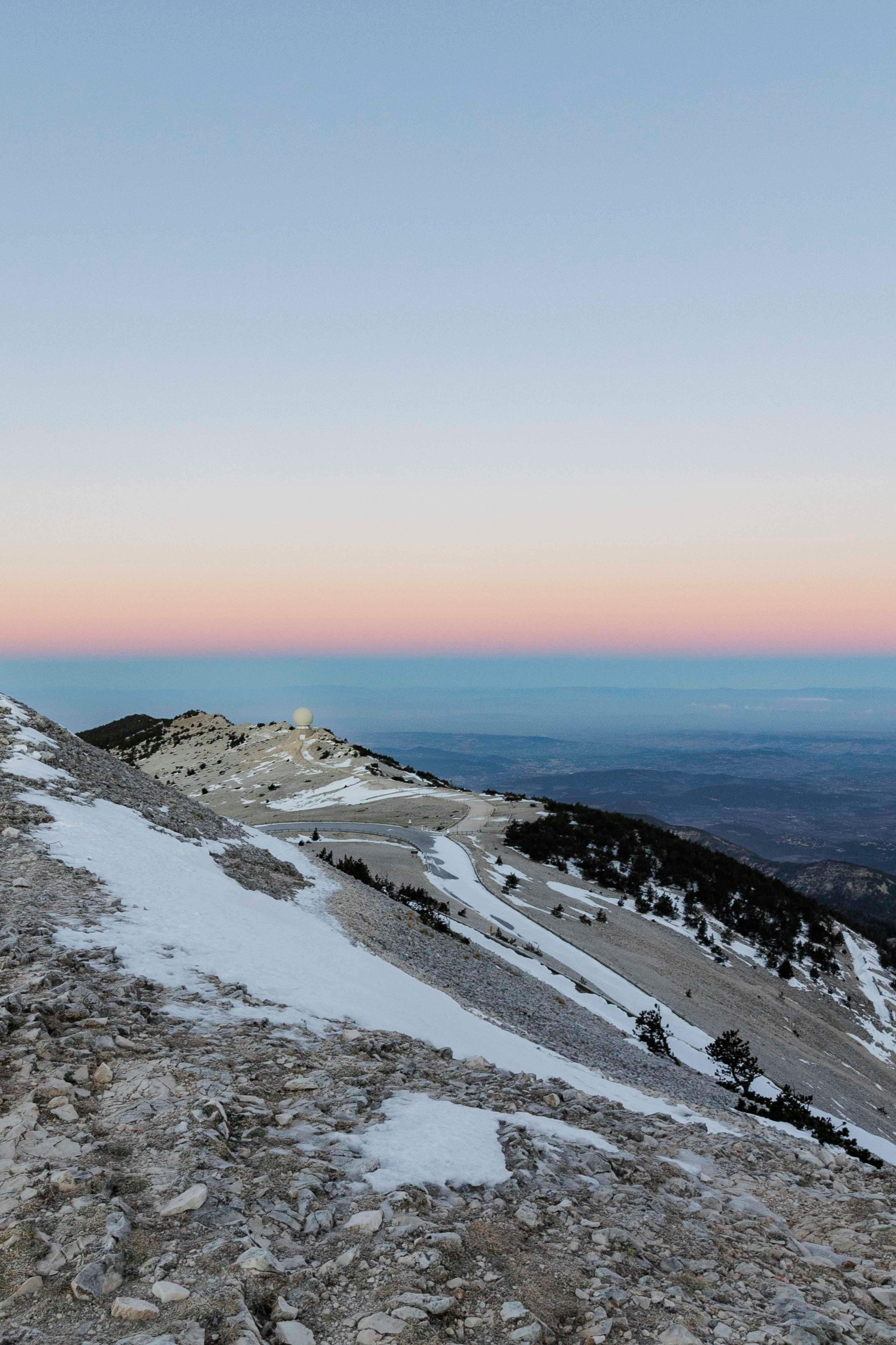 A breathtaking snowy mountain landscape captured at sunset with clear skies.