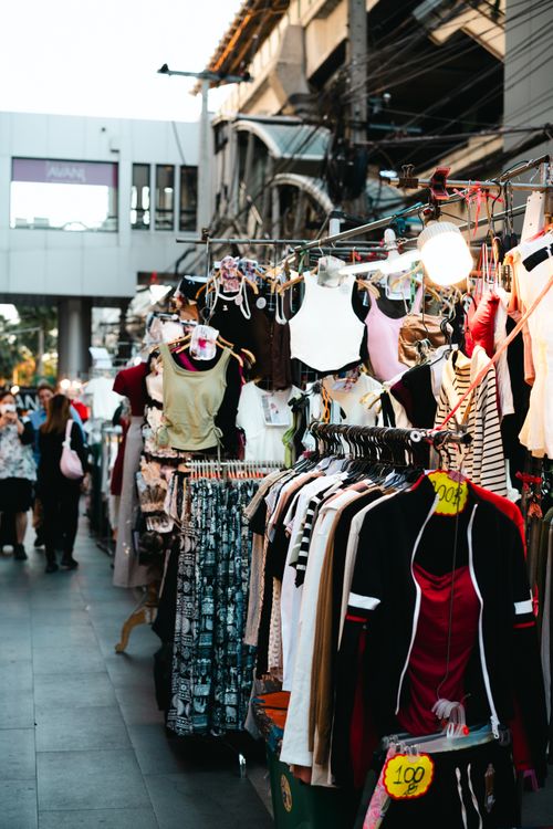 Free Explore the bustling clothing stalls of an urban street market filled with colorful attire. Stock Photo