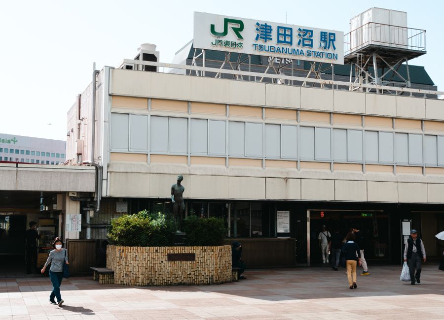 Tsudanuma Station in Narashino, Japan, showing the station facade and people walking.