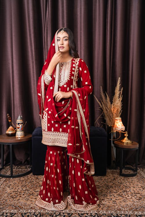 Woman Wearing a Red Traditional Dress, Standing on a Carpet