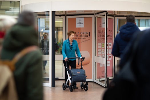 Elderly woman using walker in Utrecht shopping mall, captured candidly.