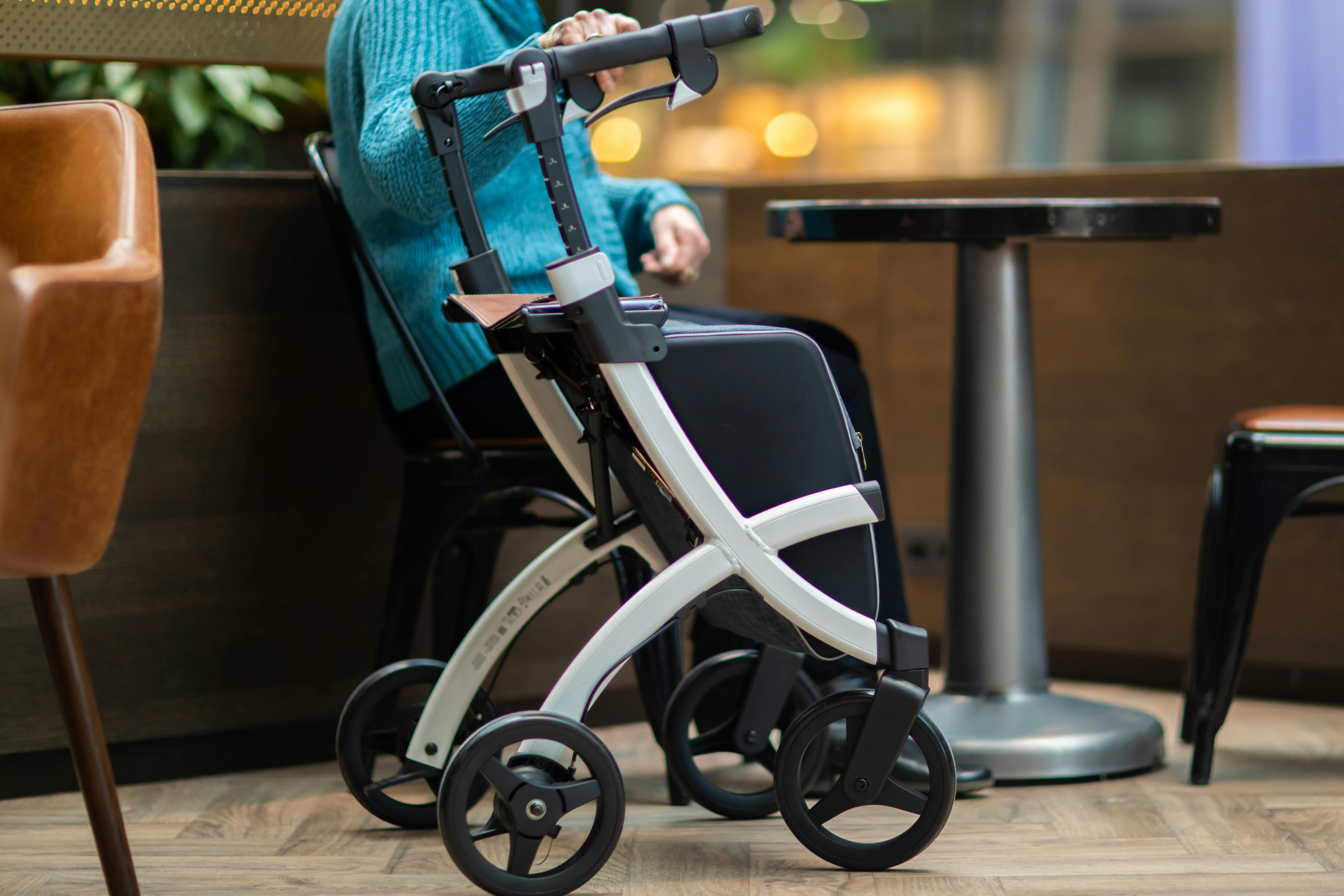 A senior woman sitting next to a rollator in a mall setting, enjoying leisure time.