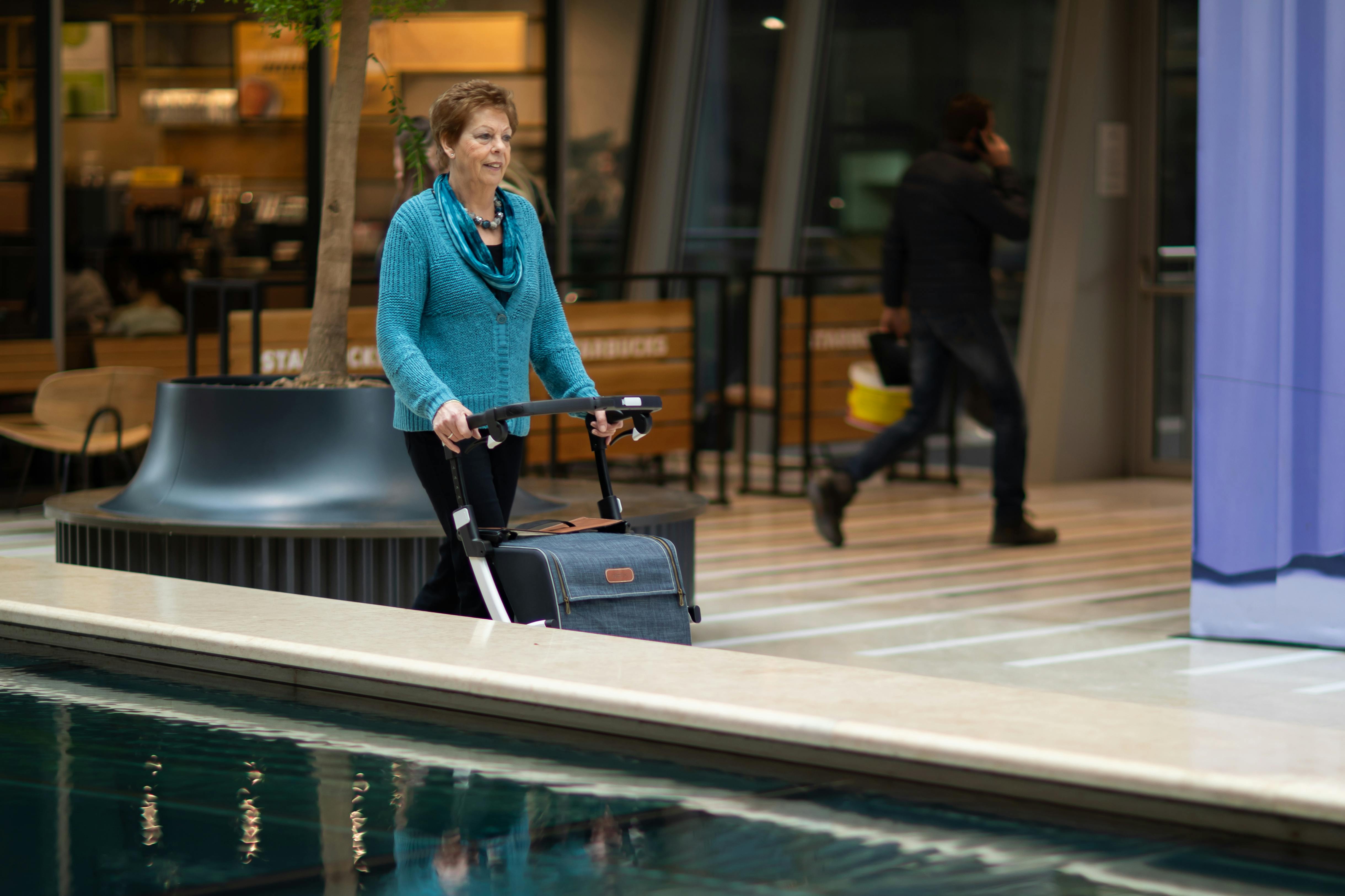 An elderly woman with a rollator walker shopping inside a modern shopping mall in Utrecht.