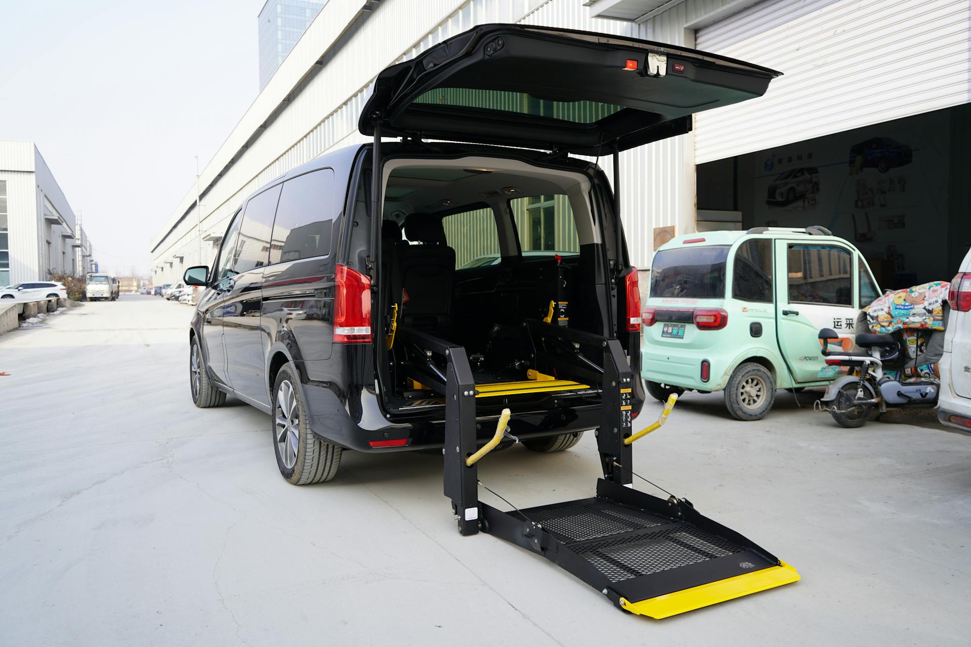 Black van with hydraulic lift in a city street, designed for accessibility.