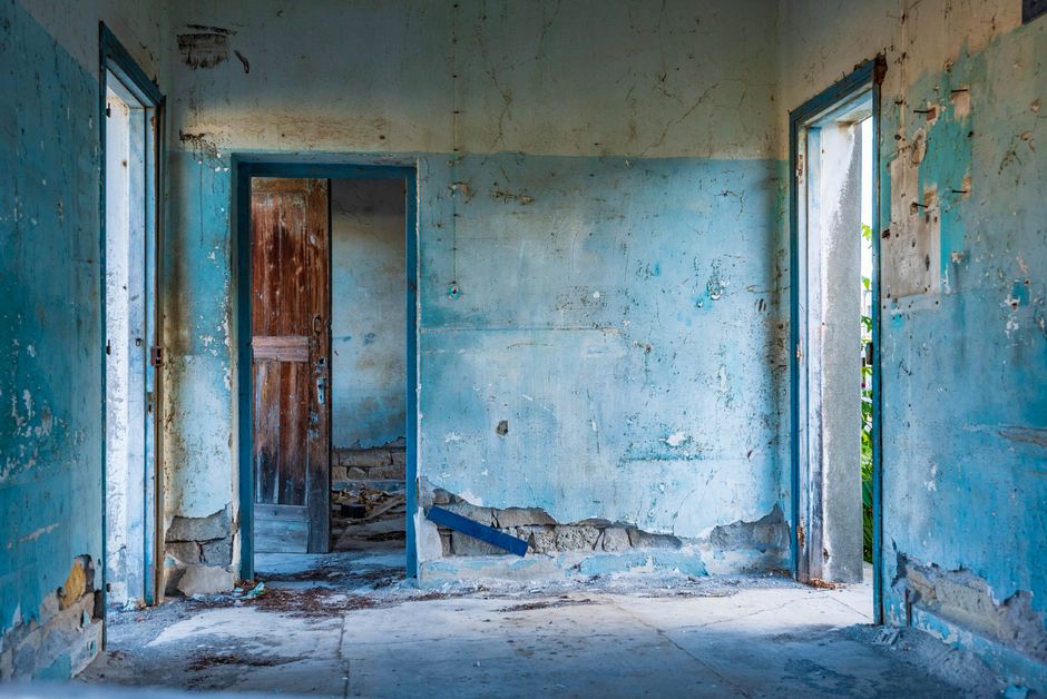 Deteriorated interior walls of an abandoned Cyprus building showing moisture damage, salt bloom and crumbling plaster at