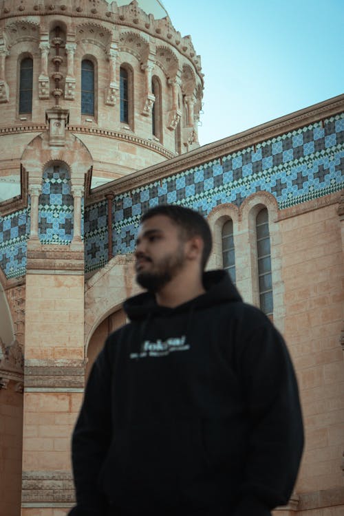 A man in a black hoodie standing in front of a church