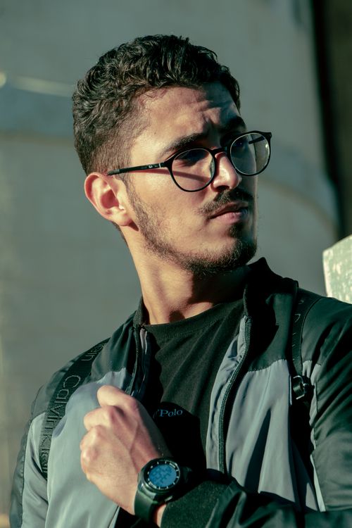 Free Stylish man in casual attire with sunglasses poses outdoors in natural light. Stock Photo