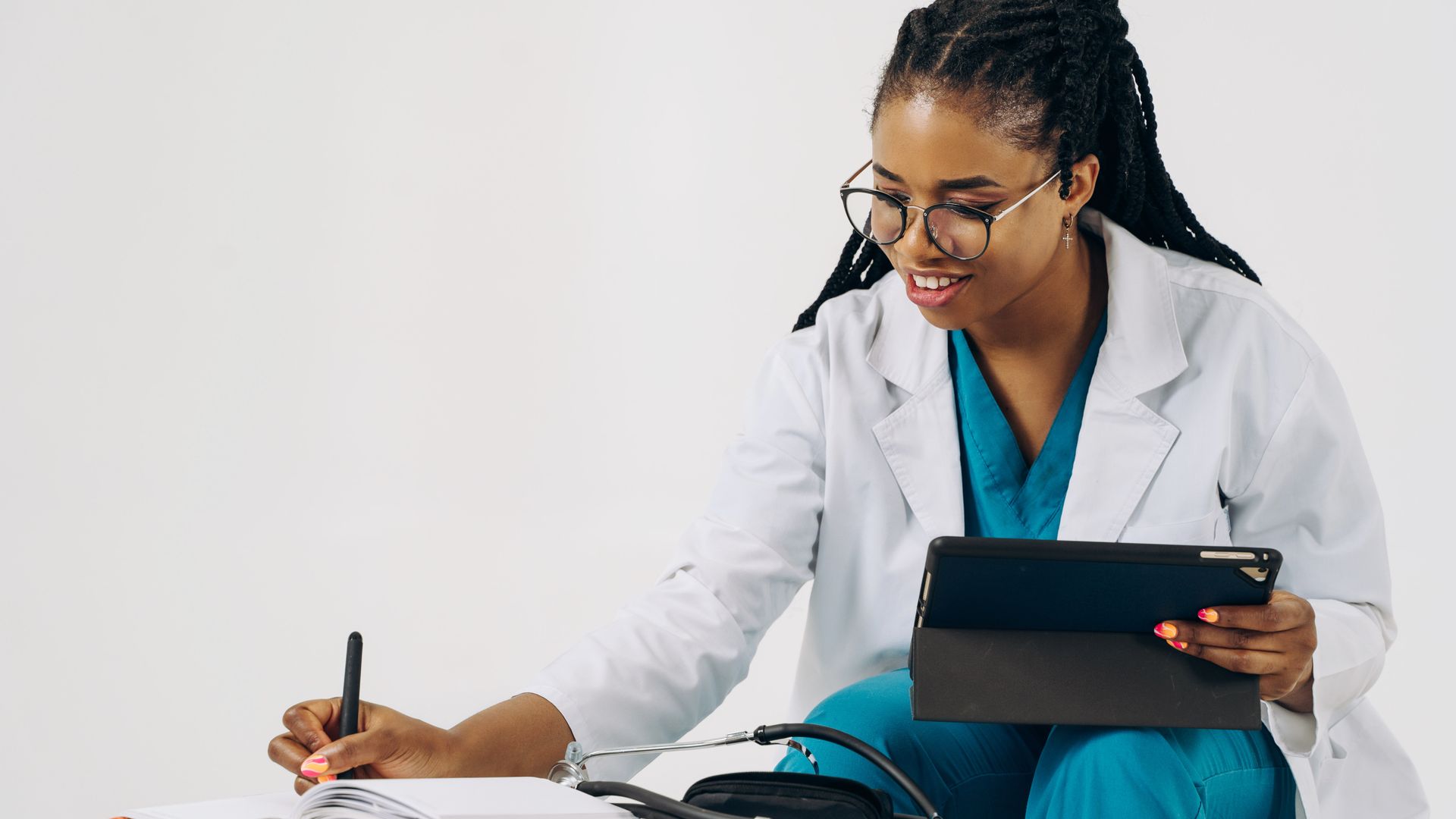 Modafinil for Remote Workers: Boosting Productivity 7 Smiling female doctor in scrubs using tablet and taking notes in a healthcare setting — modafinil for remote workers