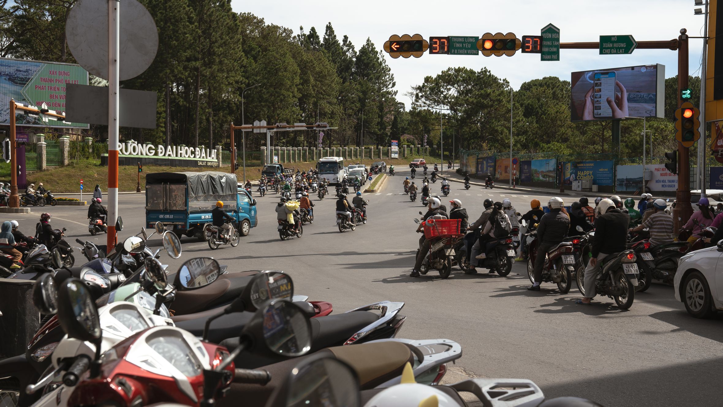 Motorbikes and vehicles navigate a busy intersection in Dalat, Vietnam, showcasing urban life and traffic.
