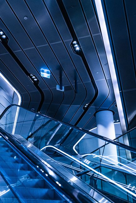 Futuristic escalator view with sleek modern architecture and vibrant lighting.