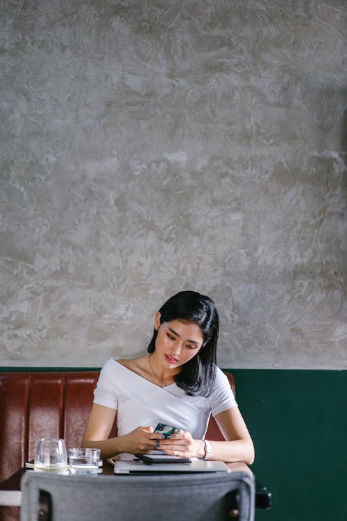 Woman Sits on Chair Holding Smartphone