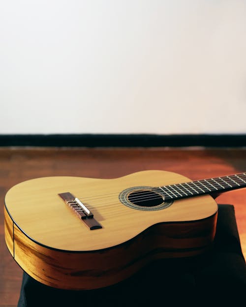 Free Brown Acoustic Guitar on Floor Near Wall Insider Room Stock Photo