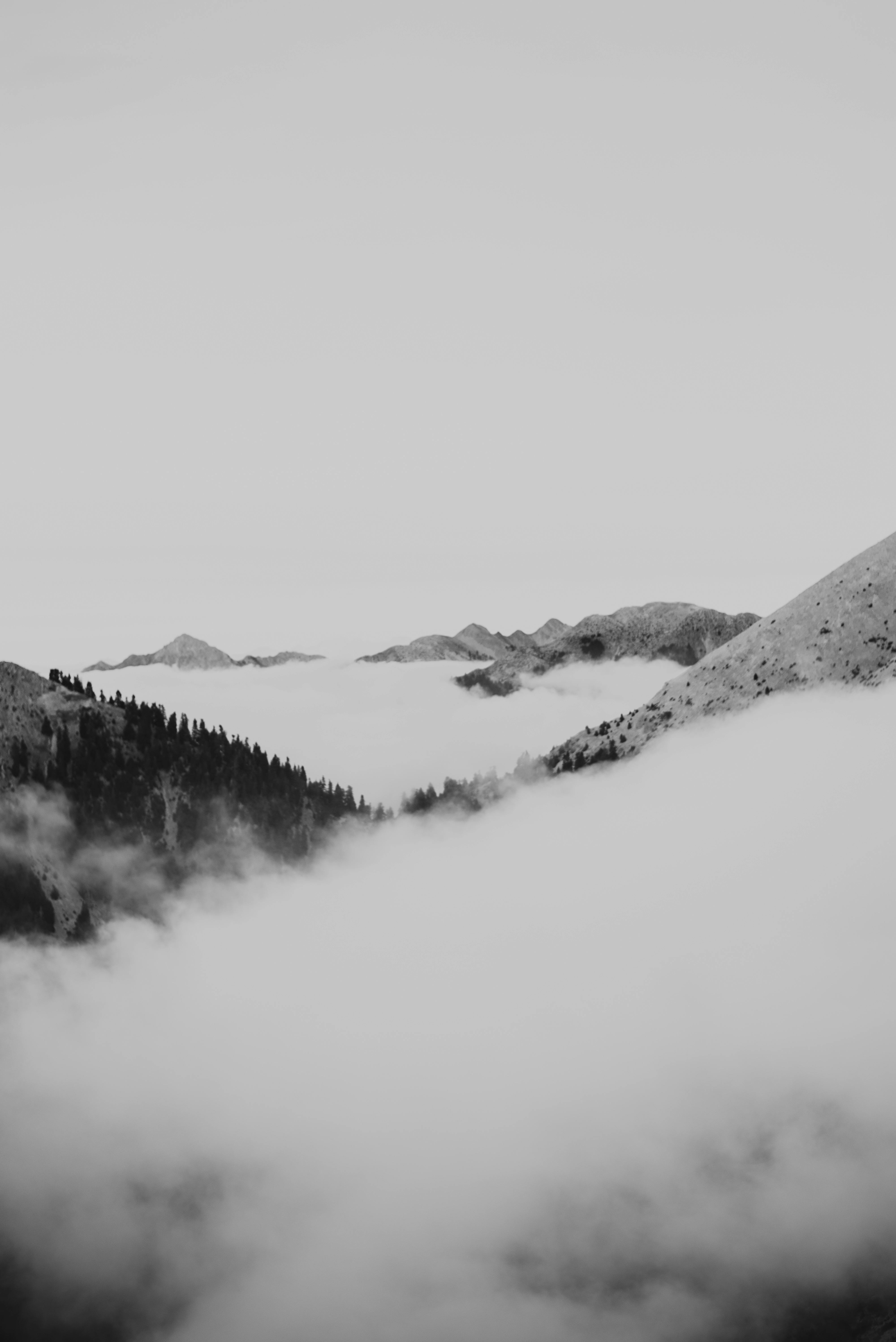 Moody black and white photo of mountain peaks surrounded by dense clouds.
