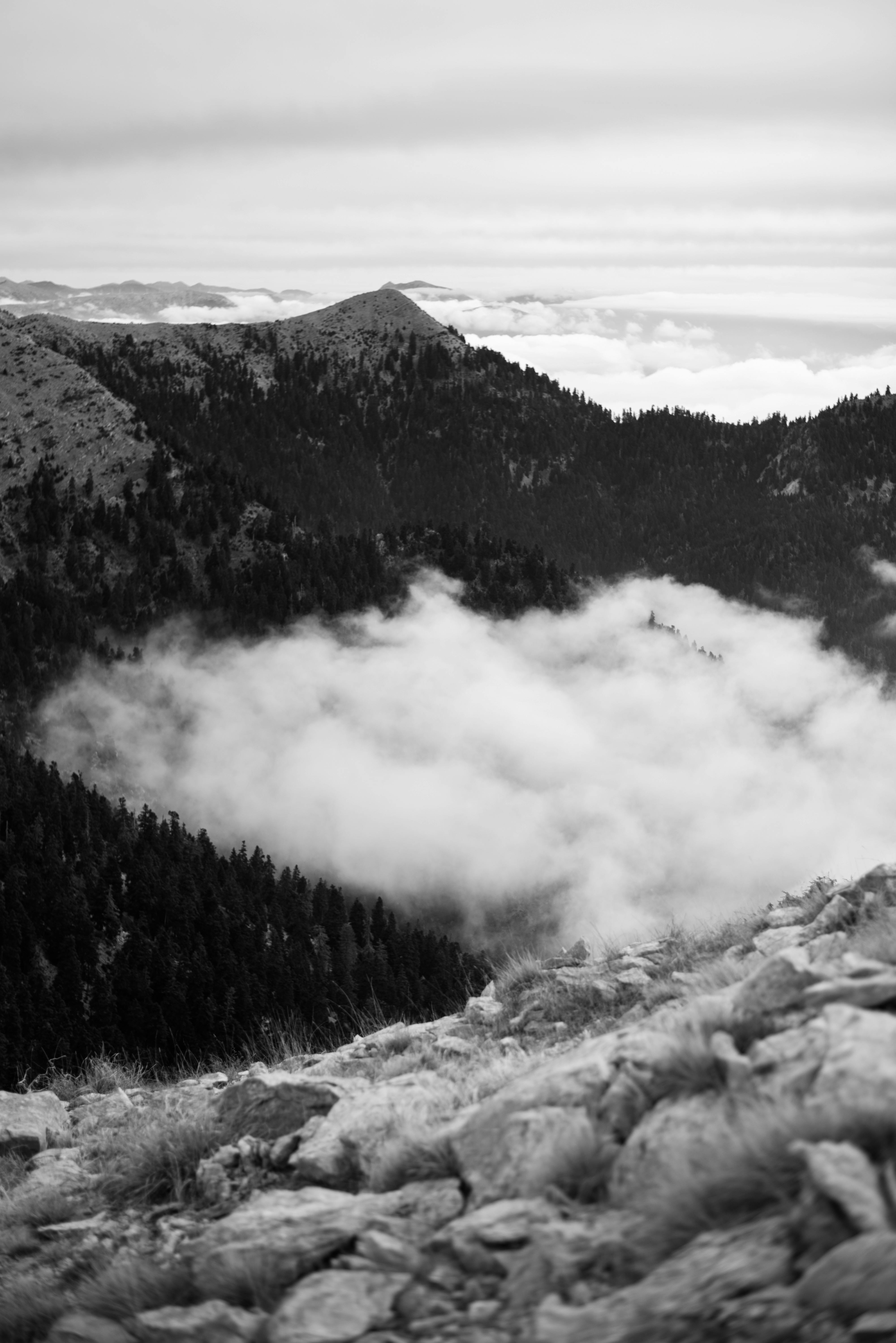 Stunning black and white view of a mountain range with clouds drifting through the peaks.