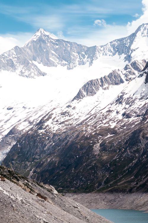 Free Breathtaking view of snow-covered peaks and serene lake under a bright sky. Stock Photo
