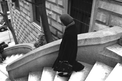 Black and White Photo of a Woman Walking Down the Stairs in City 