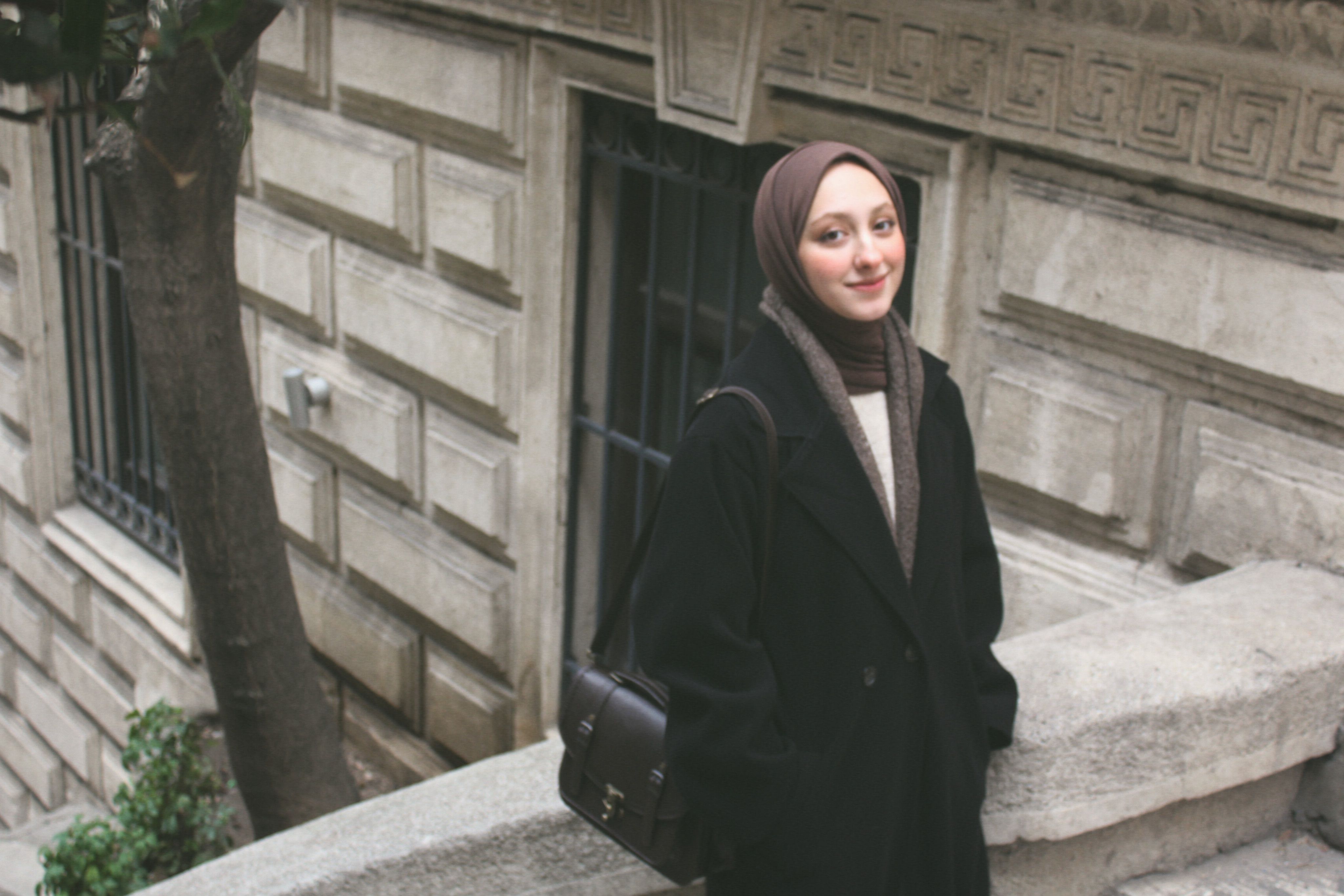 Fashionable woman wearing a headscarf smiling on a city street in winter.