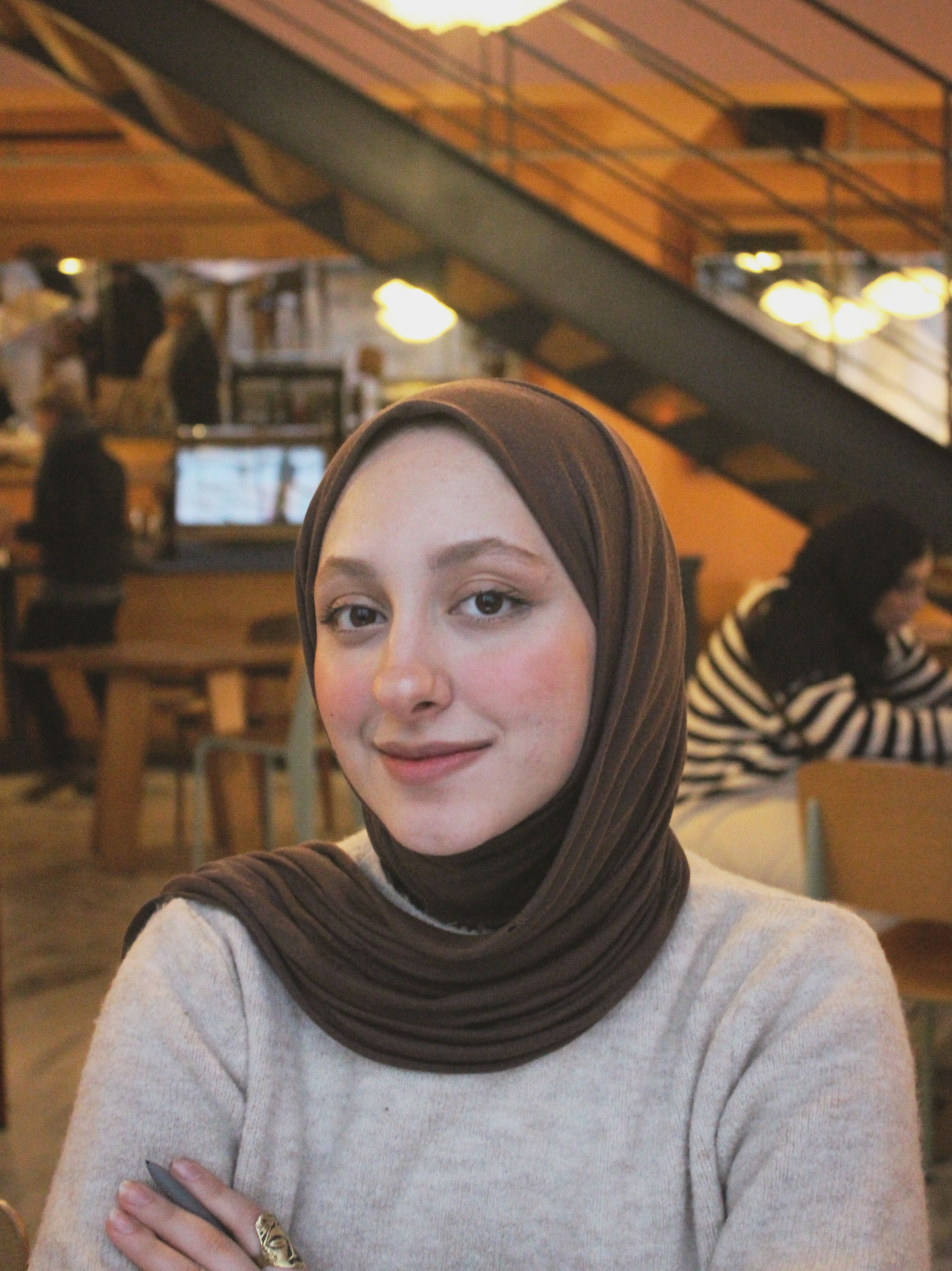 A woman wearing a hijab sitting at a table · Free Stock Photo