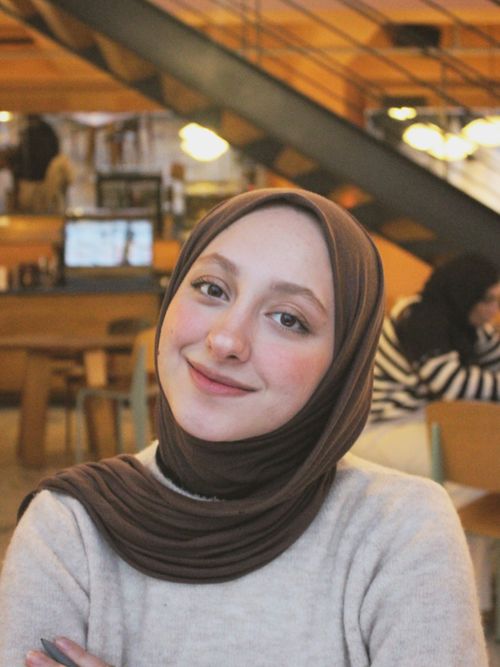 Free Portrait of a smiling woman in a headscarf, sitting in a warm and cozy cafe setting. Stock Photo