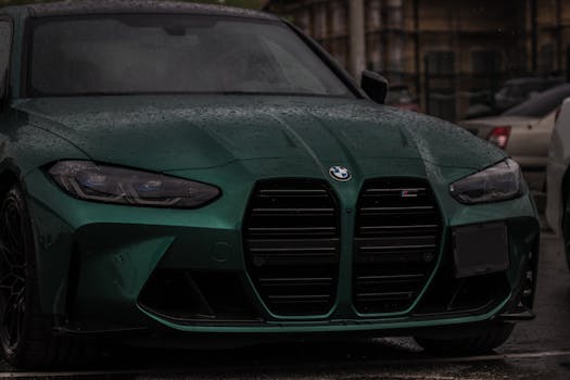 Close-up of a green BMW M4 parked on a rainy city street, highlighting its sleek design.