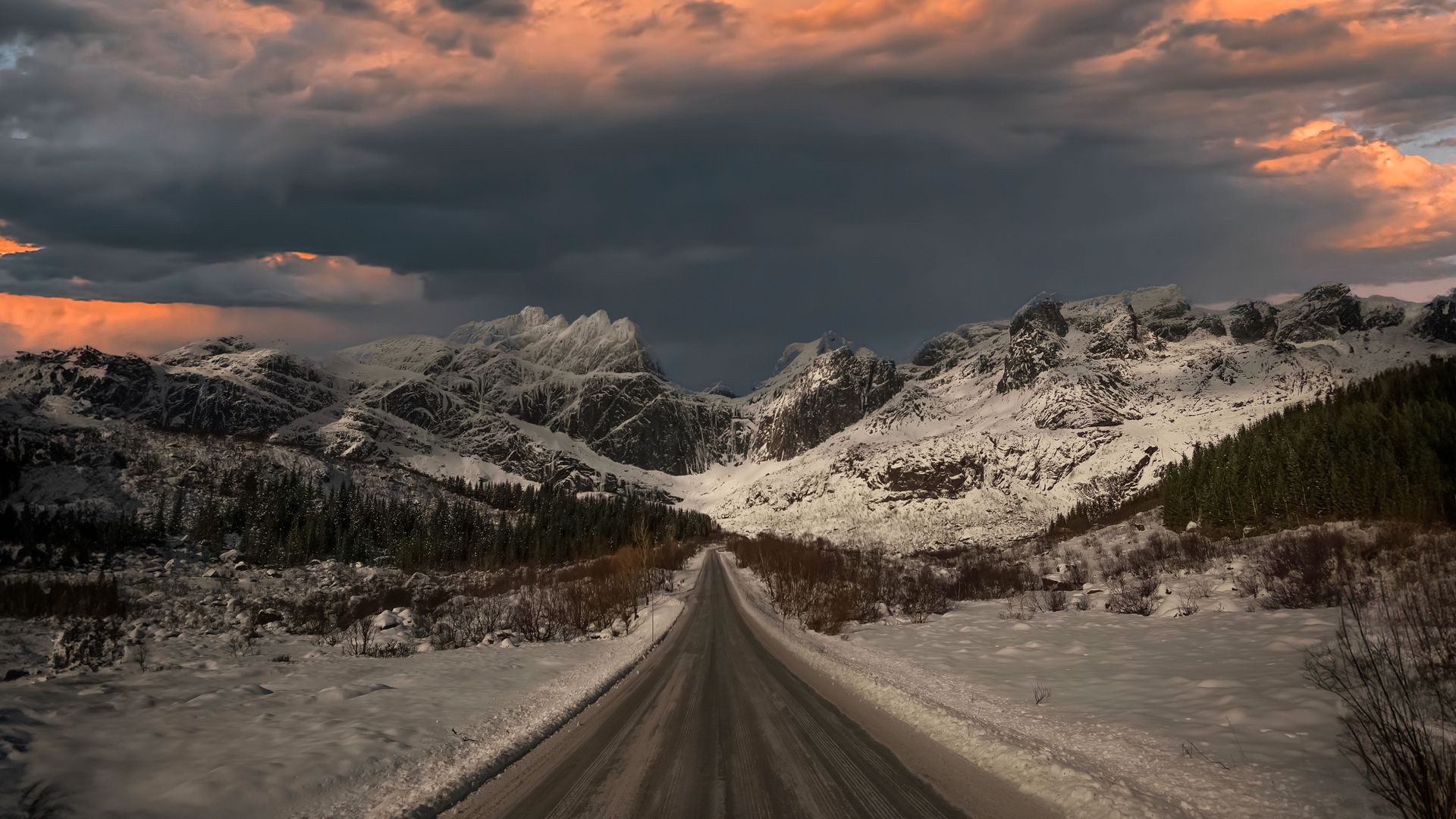 Explore a majestic winter landscape with snowy mountains and a scenic road under a colorful sunset in Nusfjord, Norge.