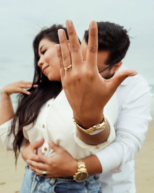 Man Hugging Woman Showing Engagement Ring