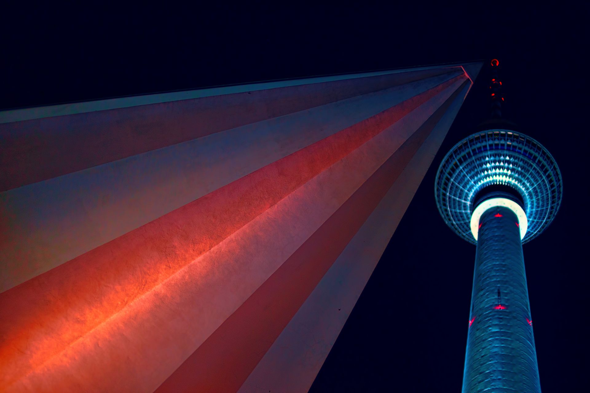 Low angle view of illuminated Berlin TV Tower with vibrant lighting against night sky.