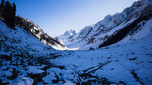 Free Scenic view of a snow-covered mountain valley with rocky terrain under clear blue sky. Stock Photo