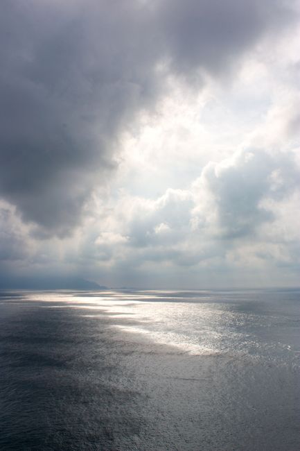 Dark clouds gather over a calm ocean, creating a dramatic and peaceful seascape.