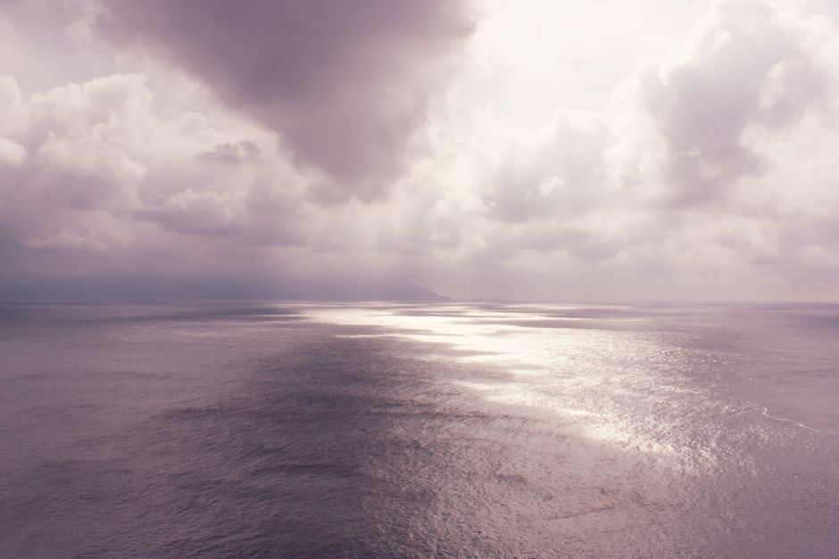 Serene ocean view beneath a dramatic, cloudy sky. Peaceful yet powerful.