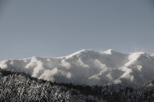 A scenic view of snow-covered mountains under a clear blue sky.