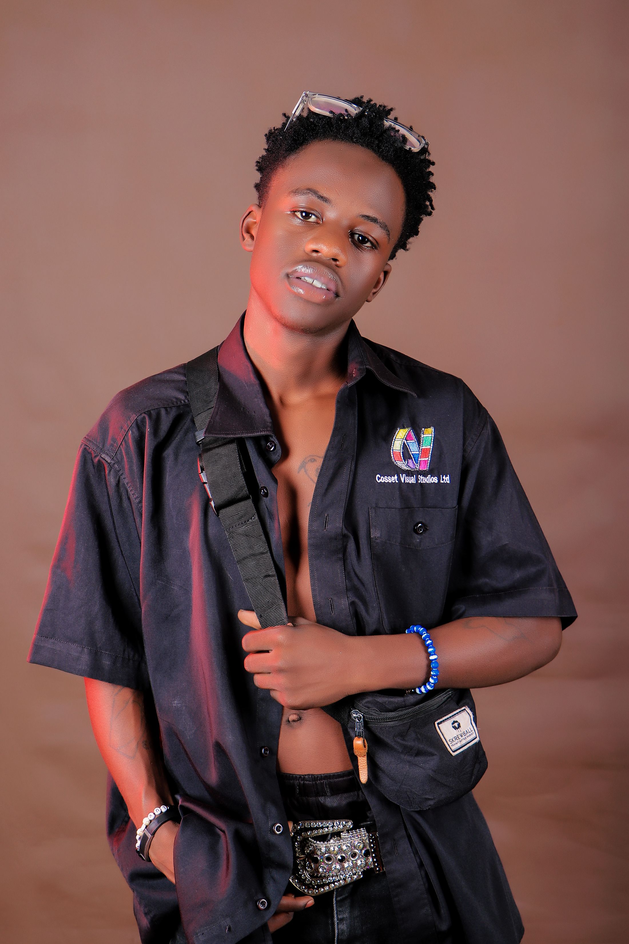 Stylish young man posing in a studio with an open shirt and accessories.