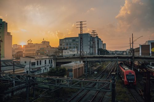 Free A cityscape view of urban train tracks and buildings at sunset, creating a warm and serene scene. Stock Photo