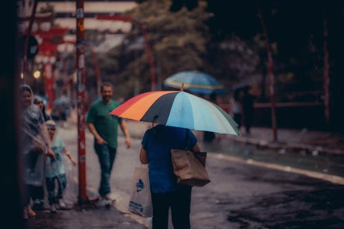 Back View of a Woman with a Colorful Umbrella Walking on a Street in City 