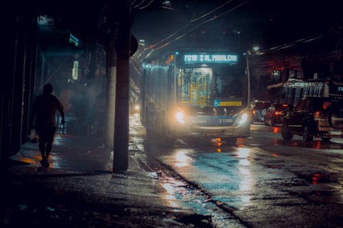 A bus is driving down a wet street at night