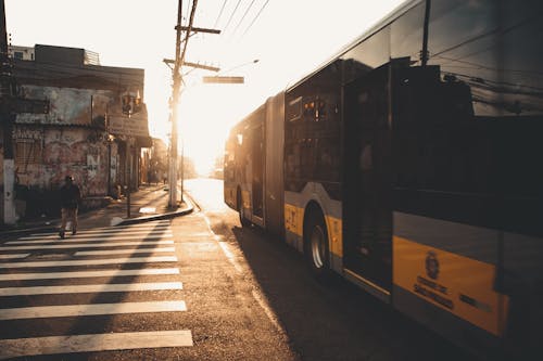 A bus is driving down the street at sunset