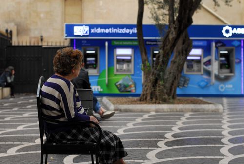 Free Senior woman seated near automatic teller machines in Baku, Azerbaijan. Stock Photo