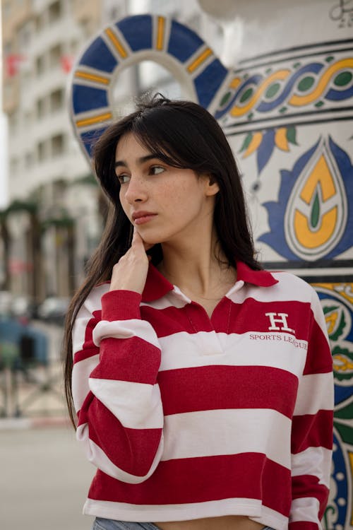 Young Woman in a Striped Blouse Standing Outside and Looking Away 