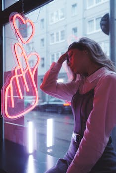 Young woman posing by a neon heart sign in urban Berlin city during daytime.
