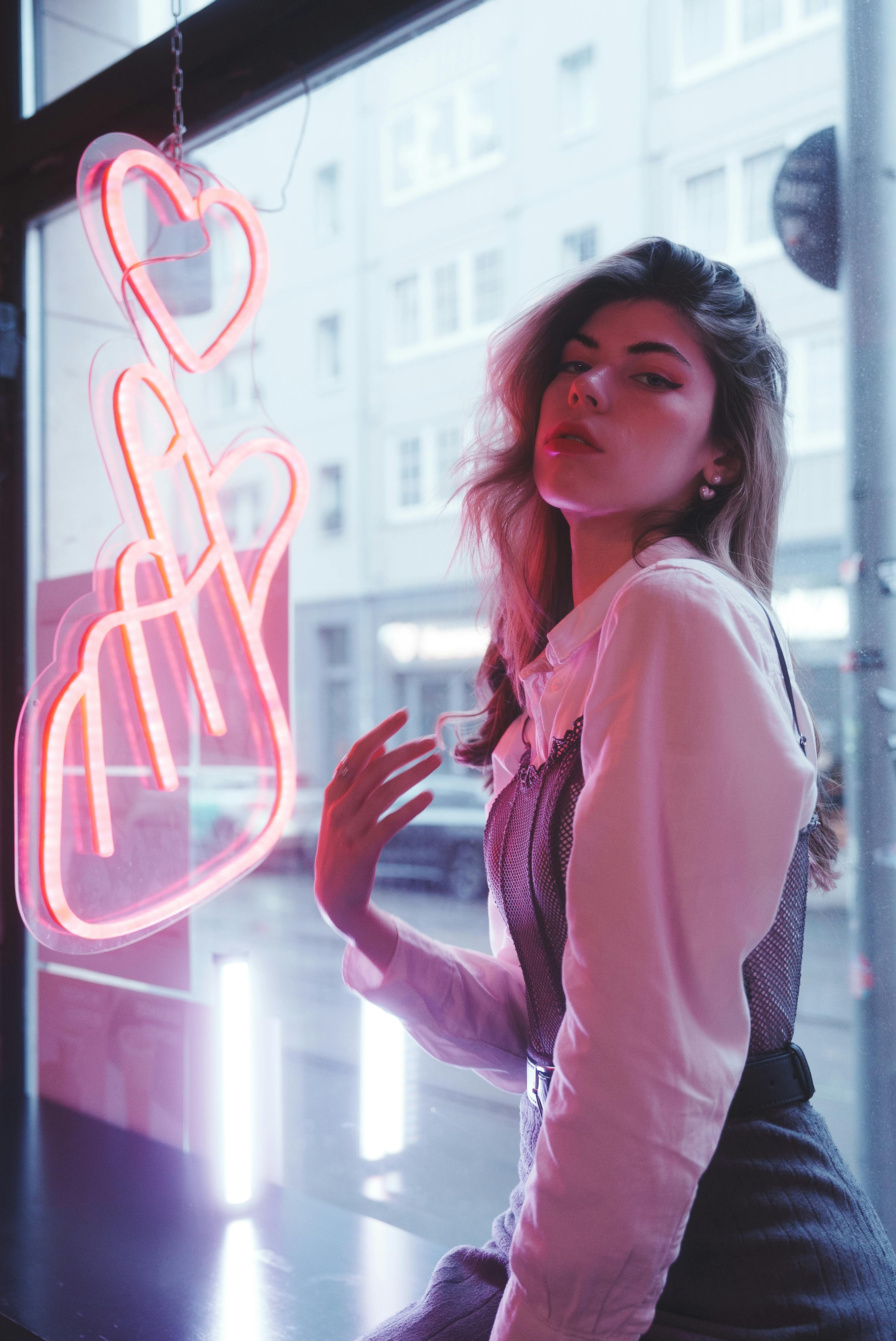 Young woman posing with neon lights in urban Berlin setting.