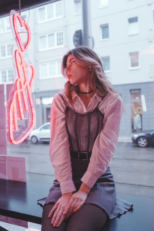 Free Fashionable woman sitting by a window with urban backdrop in Berlin, showcasing modern style. Stock Photo