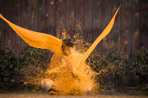 A man is covered in yellow powder and is throwing it