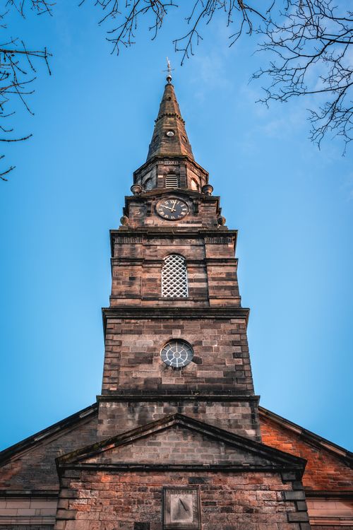 Free Gothic church tower under blue sky in Edinburgh, Scotland, capturing historic architecture. Stock Photo