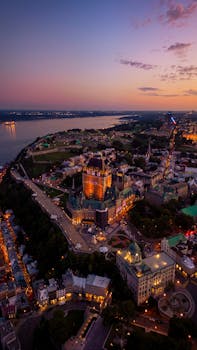 Stunning aerial view of illuminated Quebec City skyline at twilight with Chateau Frontenac.