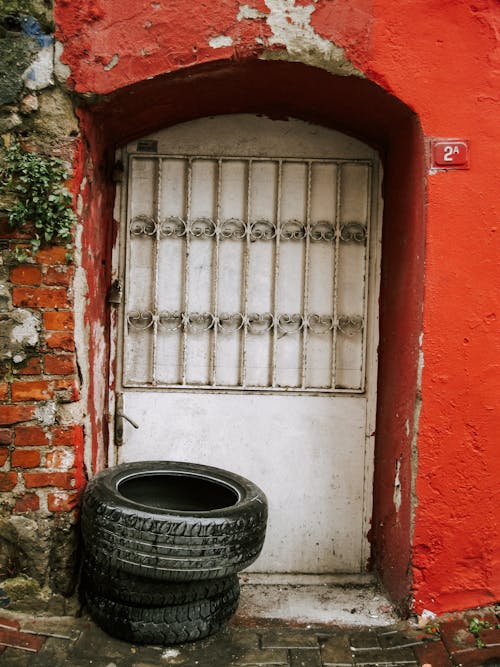 A tire is sitting in front of a red door