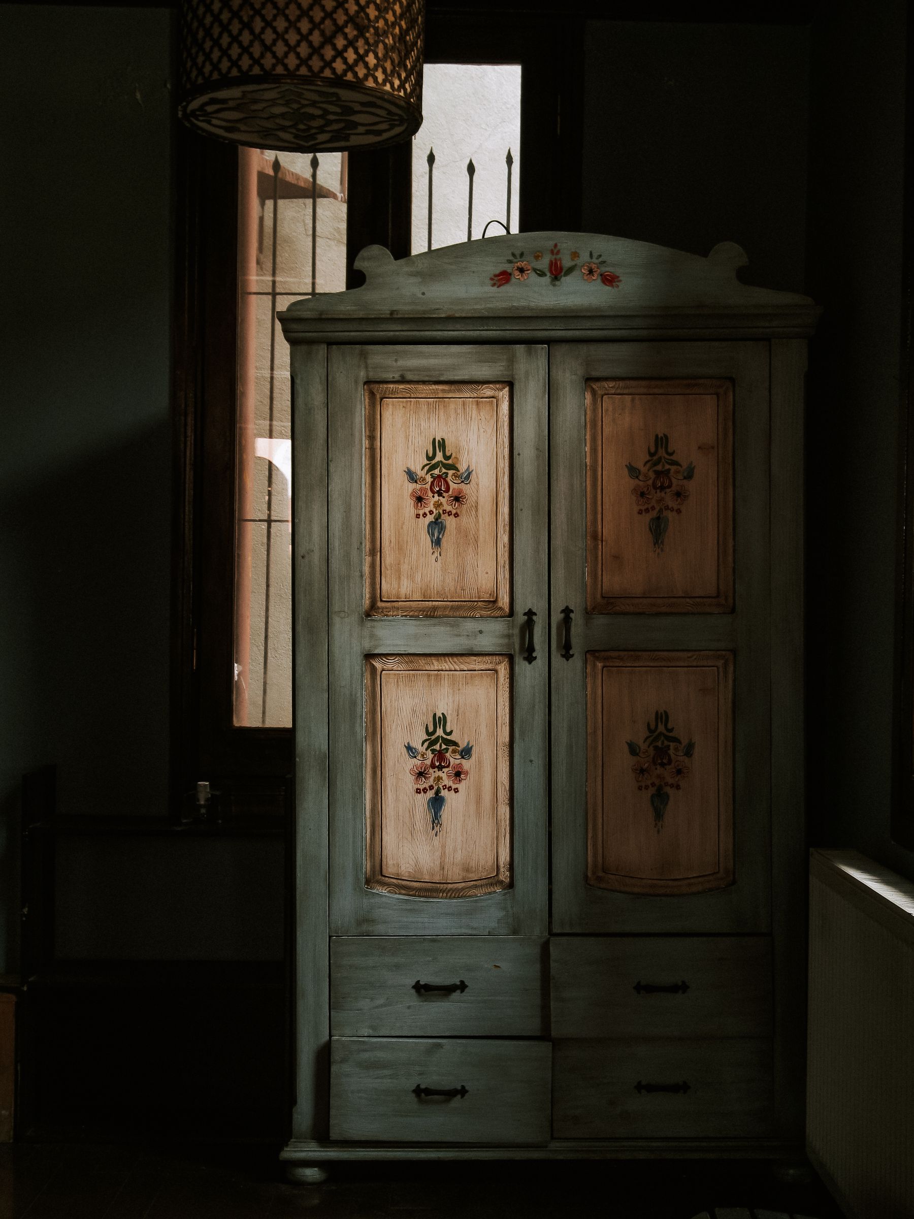Painted wardrobe with four floral panels, curved crest and four lower drawers